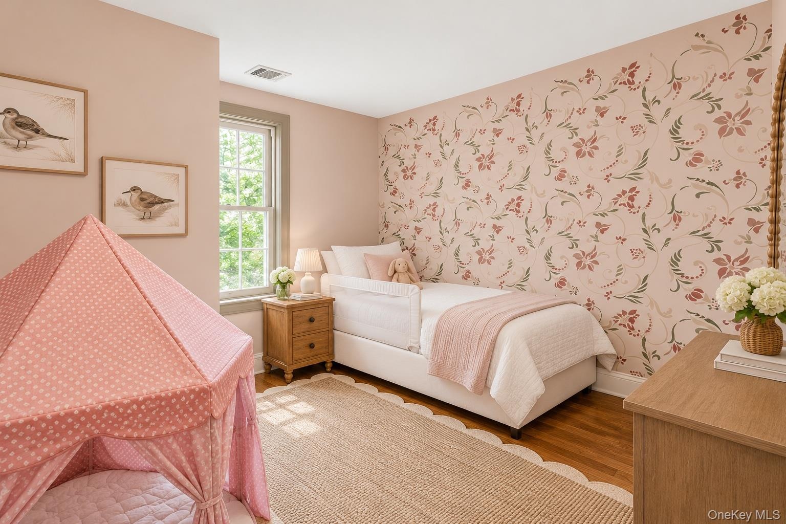Room featuring wood-finish flooring, a single-hung window with casing, and a decorative floral-patterned accent wall