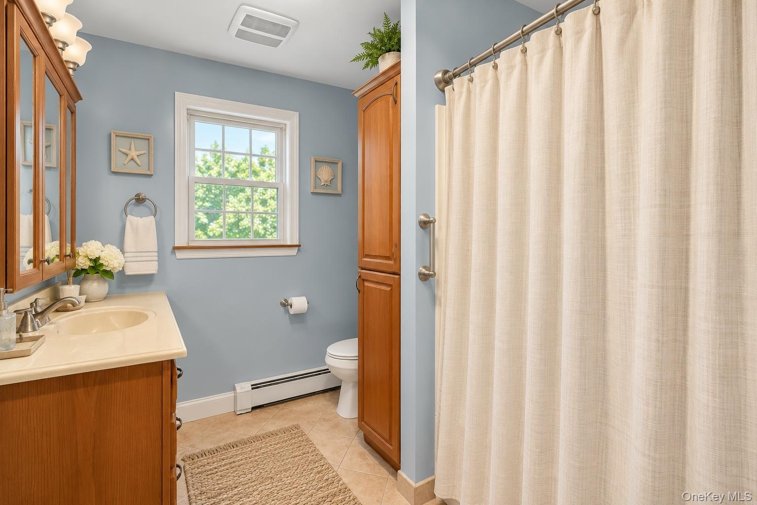 Full bathroom featuring wood-finish vanity cabinetry, a solid-surface countertop with an integrated basin, a floor-to-ceiling built-in storage cabinet