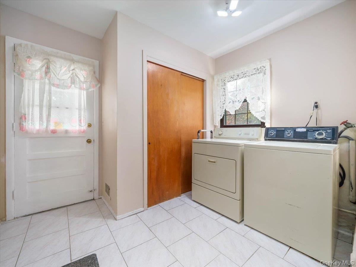 Laundry room featuring white tile flooring, wood-finish closet doors, and an exterior door with inset glass