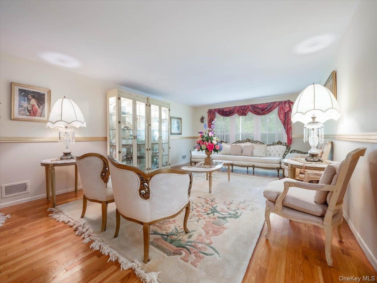 Living space featuring wood-finish flooring, chair rail molding, and a built-in illuminated glass-front display cabinet