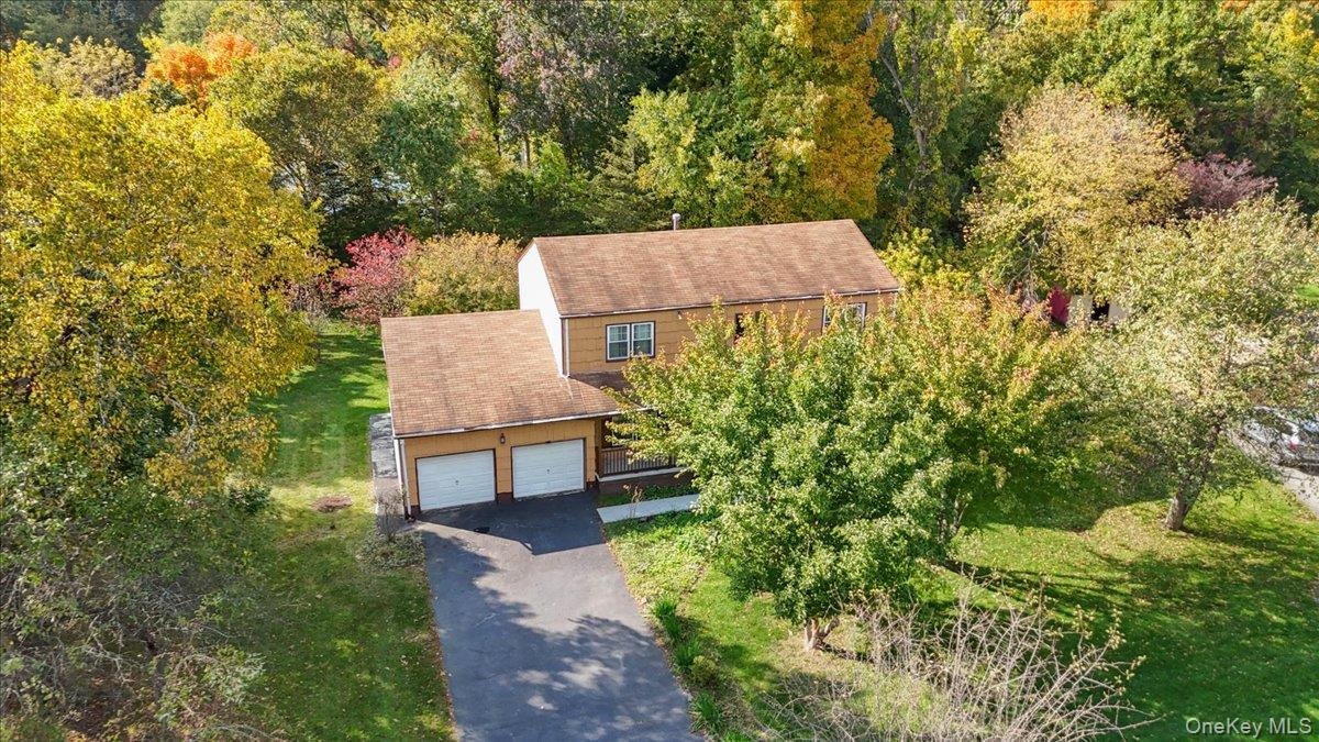 Two-story residence featuring light-toned exterior siding, a shingled roof, an attached two-car garage, and an asphalt driveway, all situated on a lot