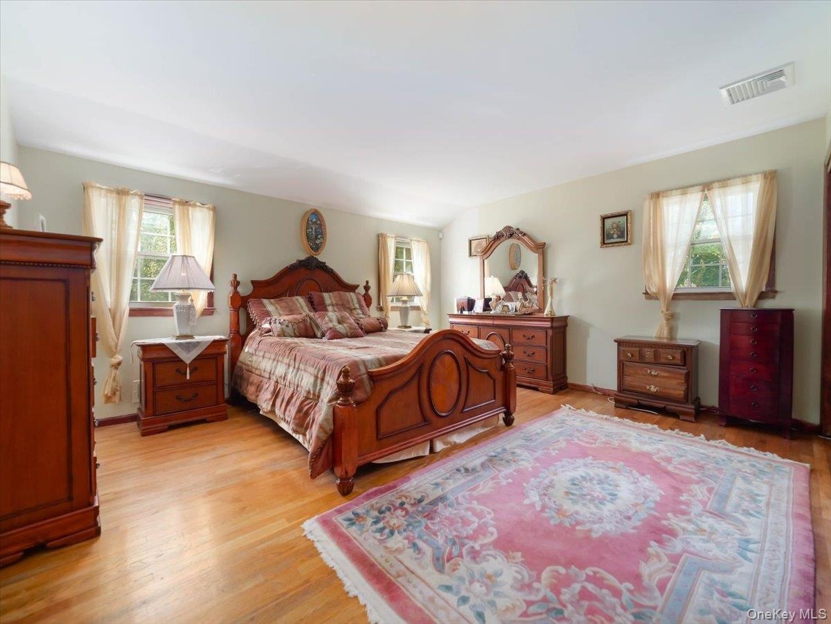 Expansive room featuring wood-finish flooring, neutral wall paint, and multiple windows with exterior exposure