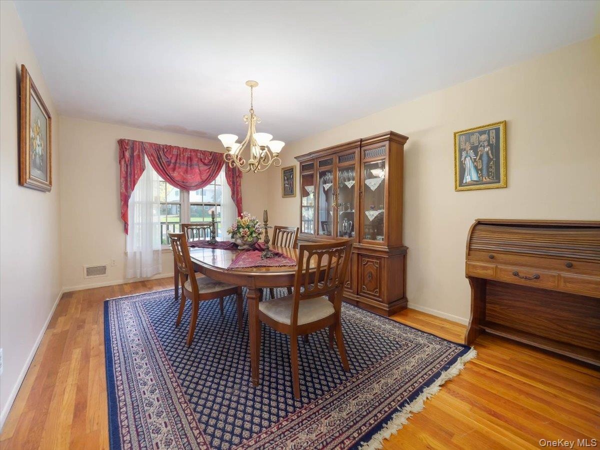 Formal dining area featuring wood-finish flooring and a multi-arm chandelier