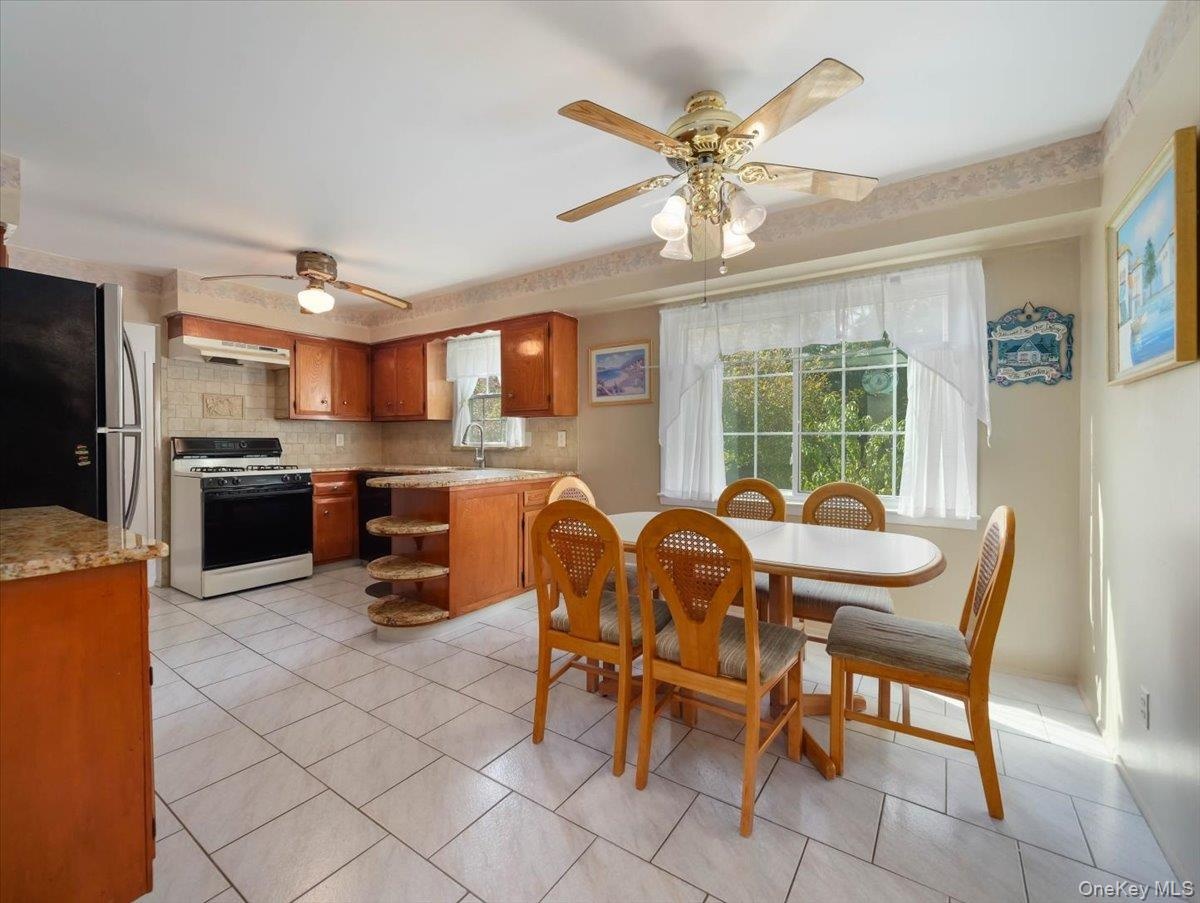 Kitchen featuring wood cabinetry, stone-finish countertops, tile flooring, and integrated ceiling fans with light fixtures