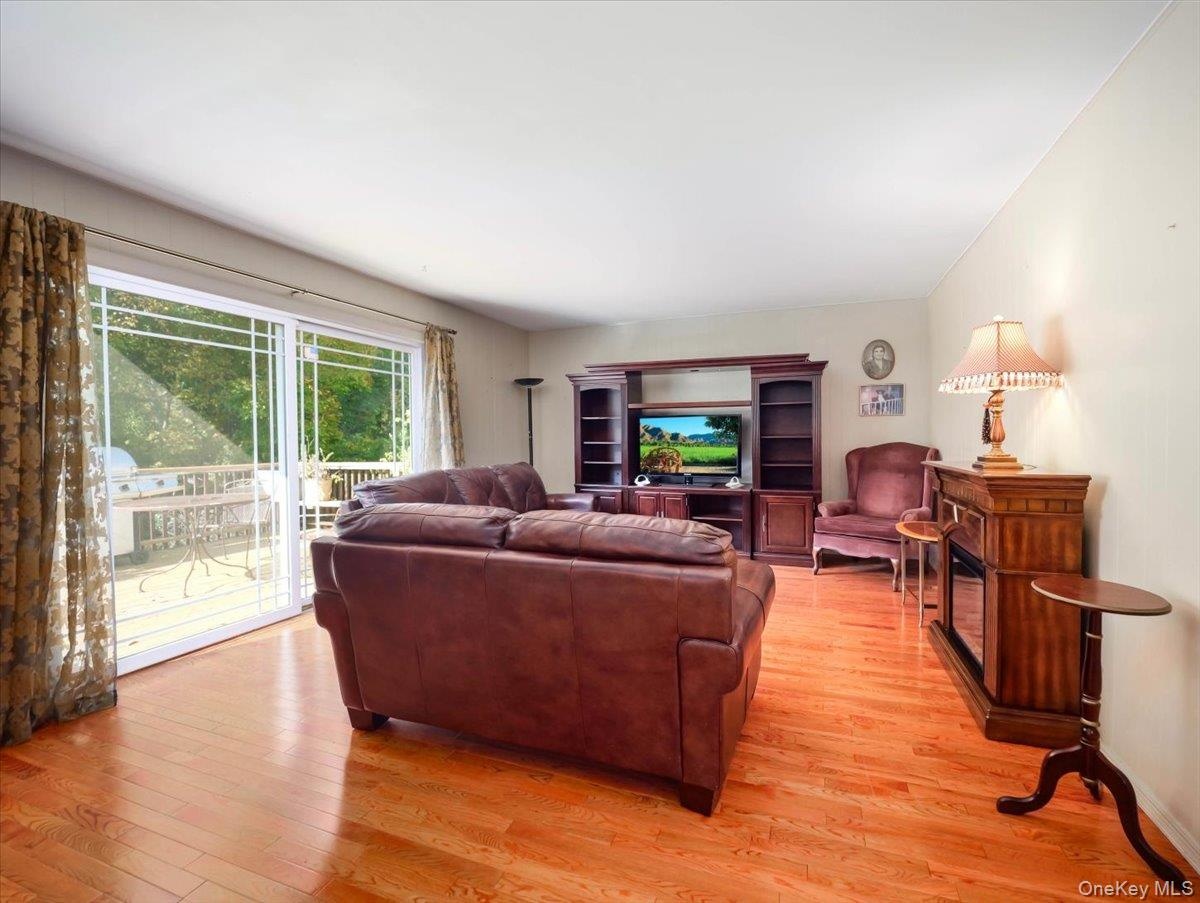 Living room featuring wood-finish flooring, a built-in media cabinet, and large glass sliding doors