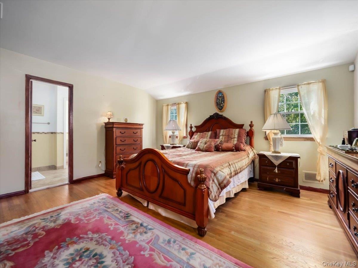 Bedroom featuring wood-finish flooring, dual windows, and an arched entryway
