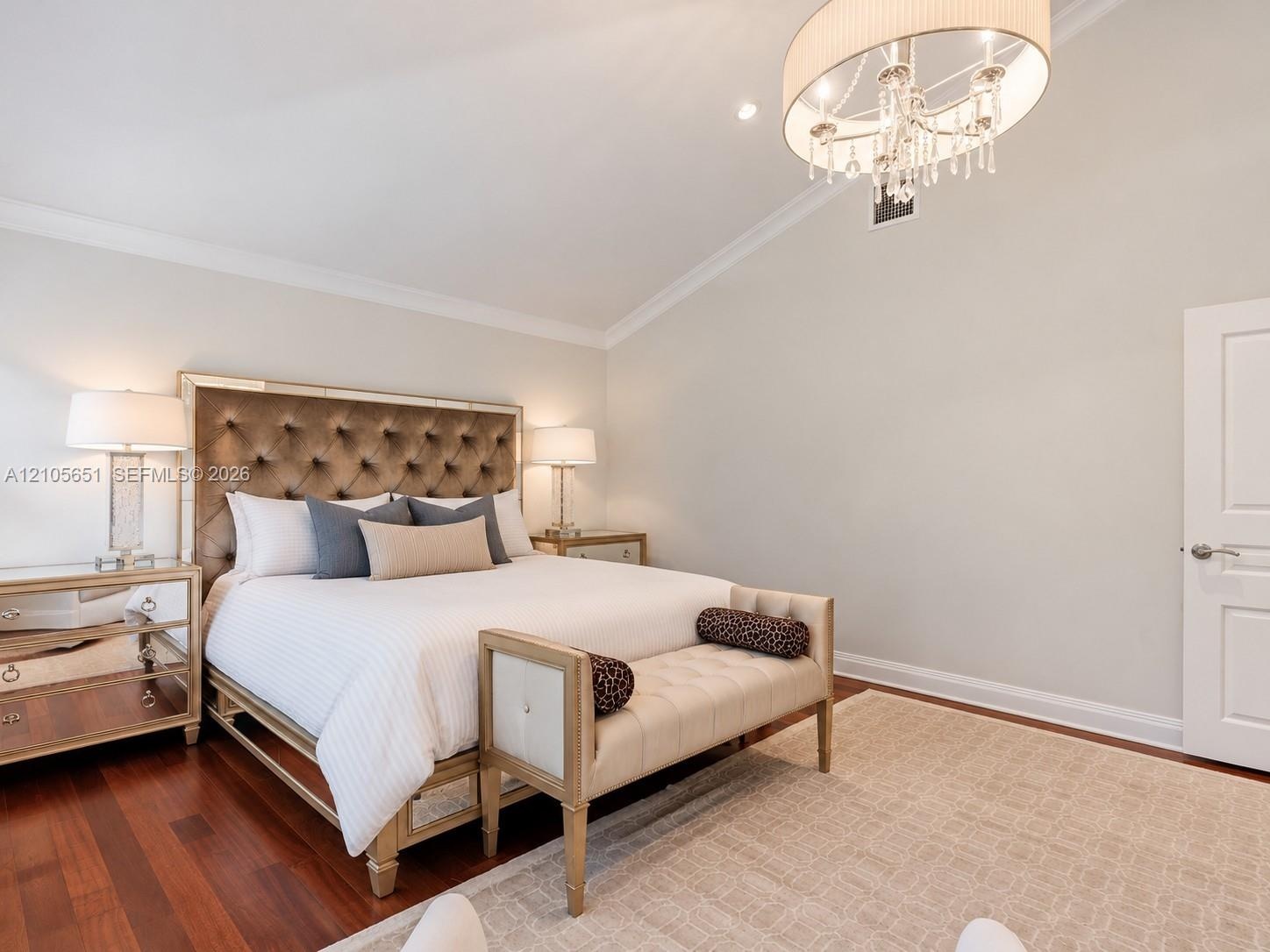 Vaulted ceiling featuring a crystal drum chandelier, wood-finish flooring, and a multi-panel interior door