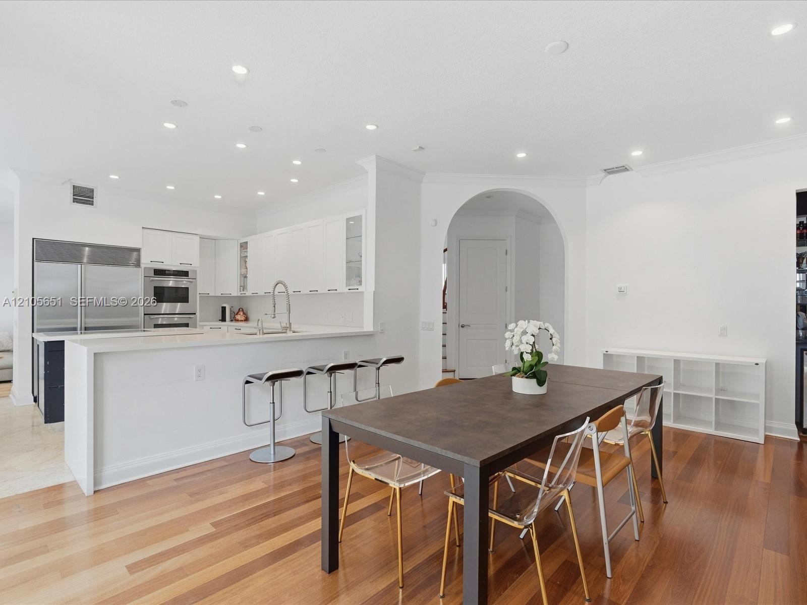 Open-concept interior featuring wood-finish flooring, recessed lighting, and a kitchen equipped with stainless steel appliances, crisp white cabinetry