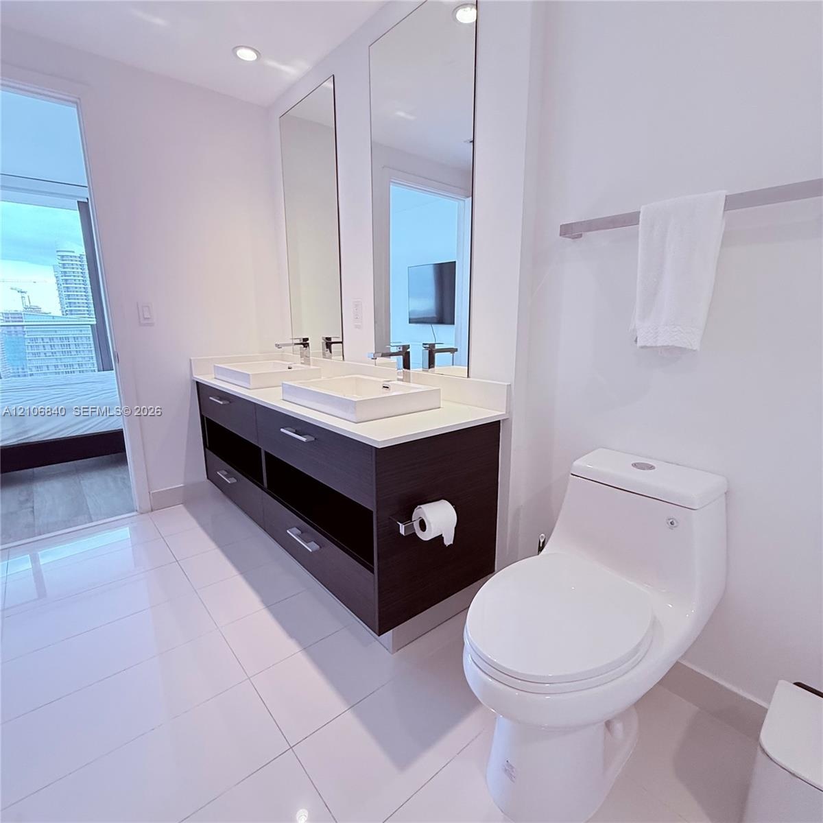 Dual-vanity cabinet featuring a dark wood-finish, stone-surfaced countertop, square vessel sinks, polished chrome fixtures, and full-length vertical m