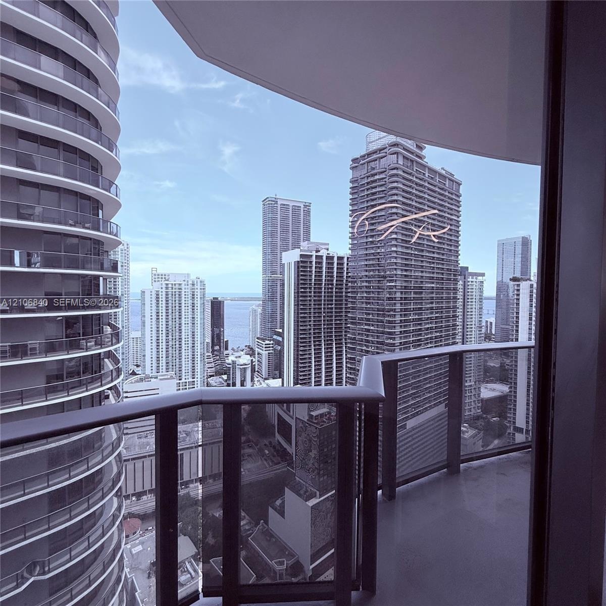 Covered private balcony featuring glass railings and panoramic urban skyline scenery