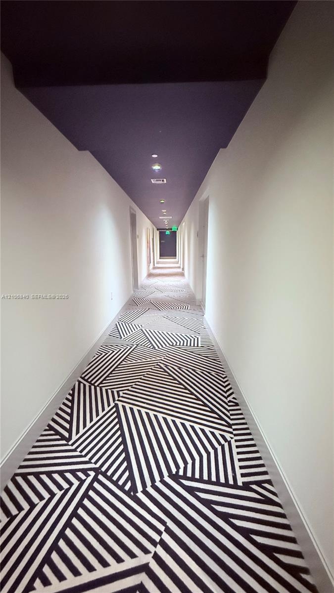 Hallway featuring geometric patterned carpeting, a deep-toned ceiling, and recessed lighting