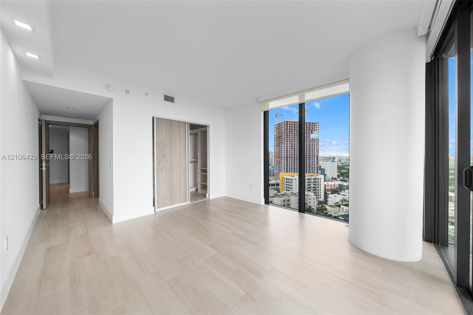 Floor-to-ceiling windows, wood-finish flooring, recessed lighting, and built-in closet with sliding doors