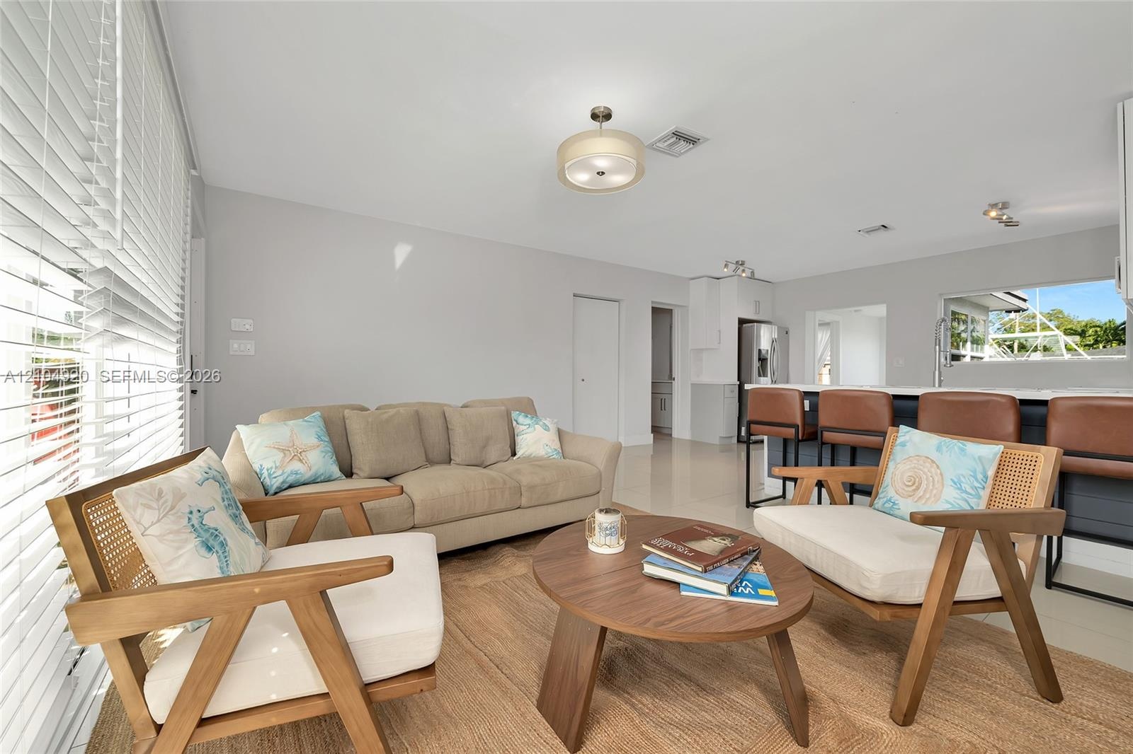Open-concept living space featuring high-gloss tile flooring, neutral wall tones, recessed lighting, and a breakfast bar with built-in cabinetry