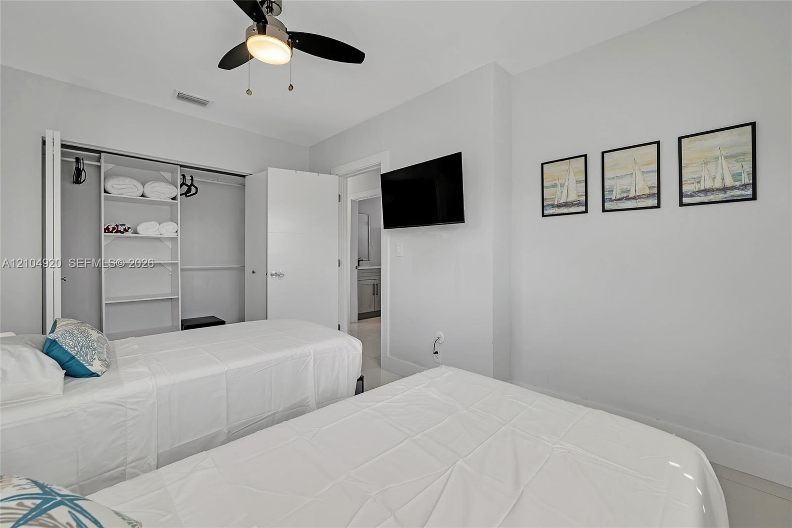 Bedroom featuring high ceilings, a ceiling fan with integrated lighting, and a reach-in closet with built-in shelving