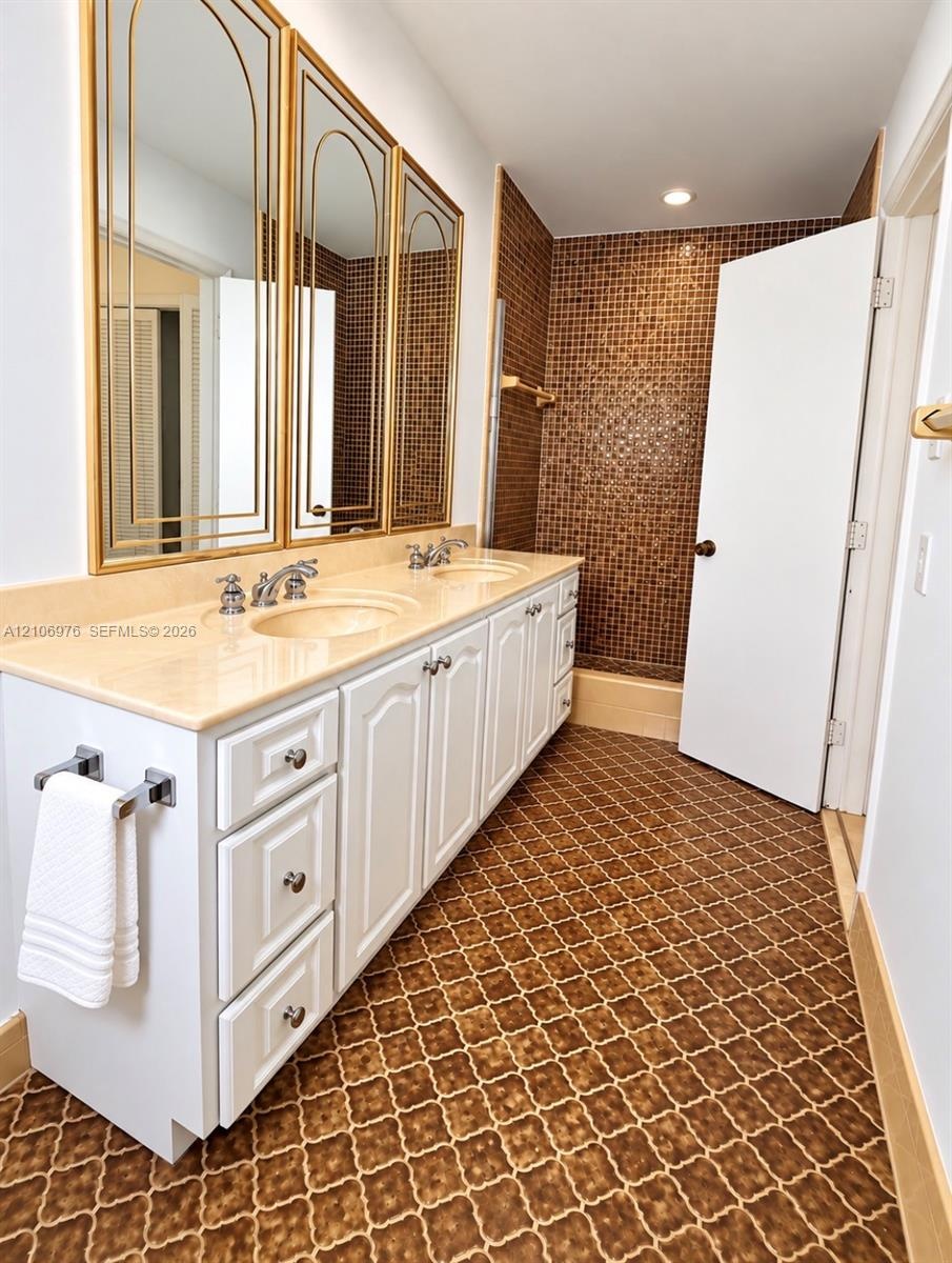 Double vanity featuring white cabinetry, a solid-surface countertop with integrated sinks, and polished metal faucets