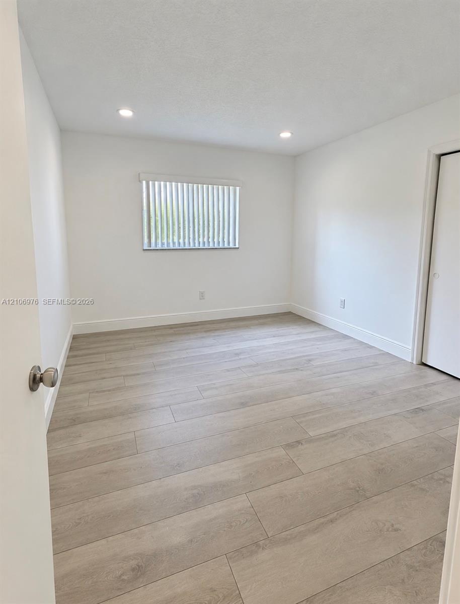 Interior space featuring wood-finish flooring, neutral walls, recessed lighting, vertical window blinds, and a built-in closet