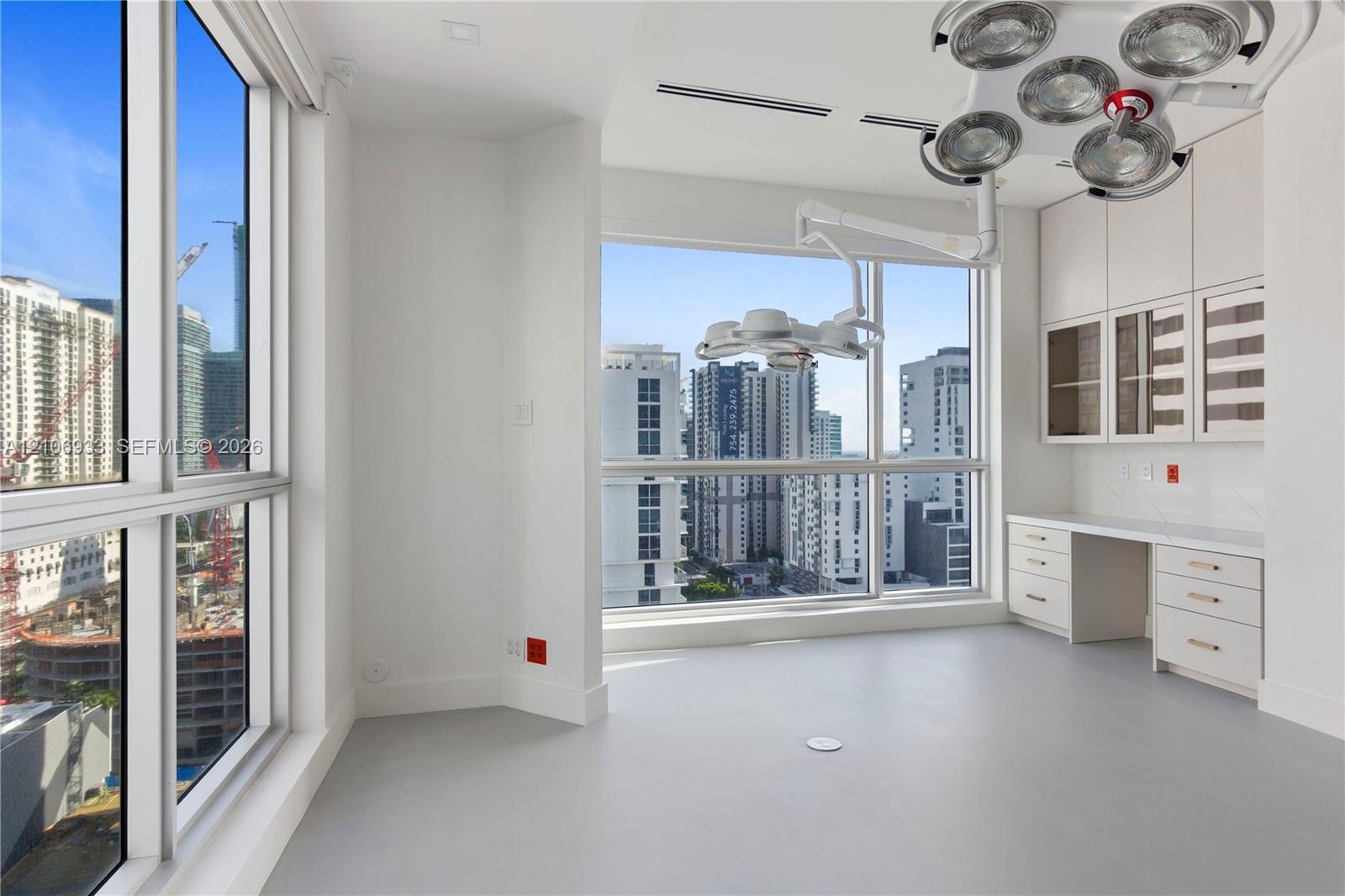 Floor-to-ceiling windows, built-in cabinetry with glass-front uppers, integrated desk surface, ceiling-mounted adjustable lighting fixtures, and solid