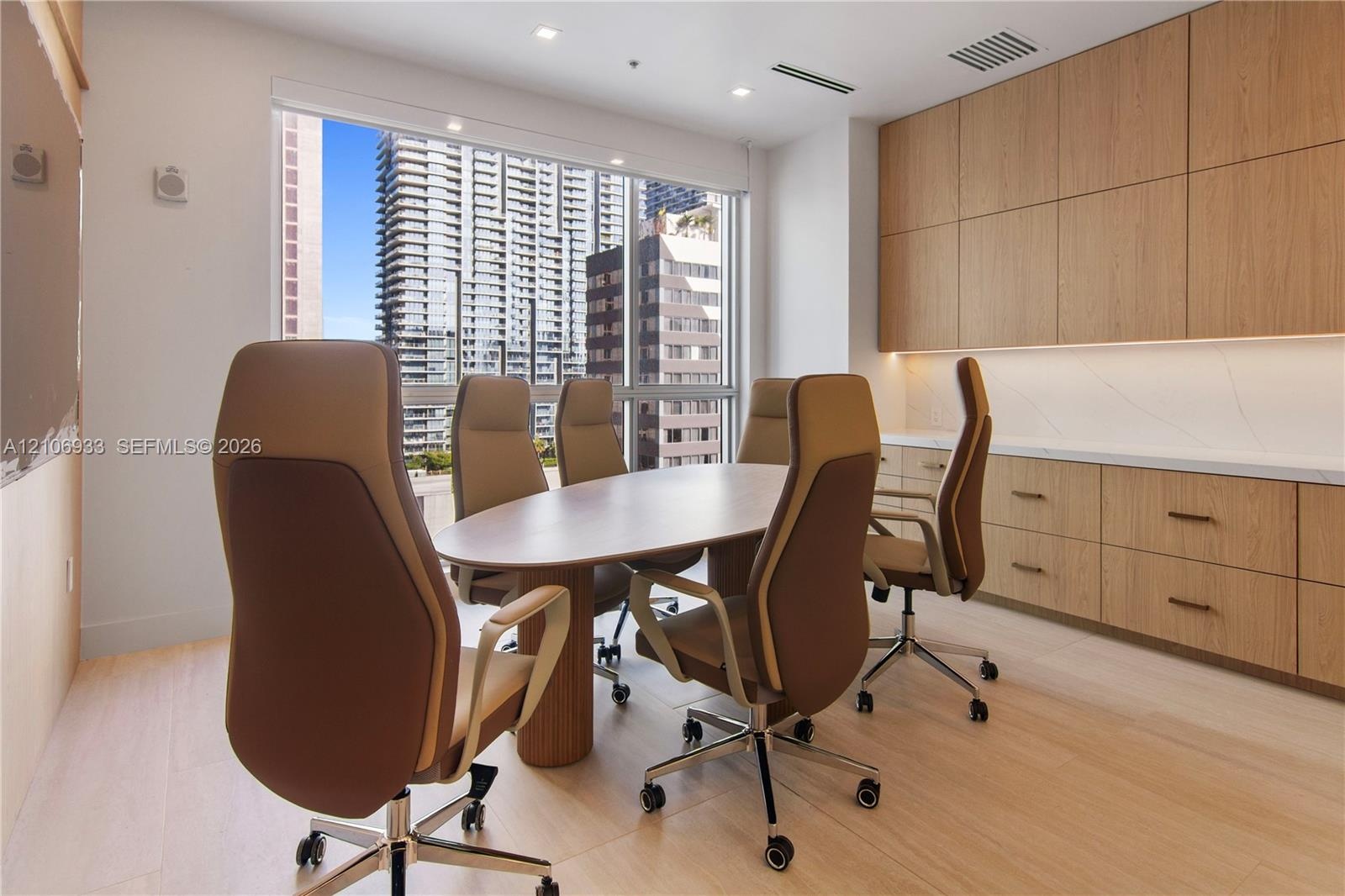 Built-in wood-finish cabinetry with stone-surface countertop, floor-to-ceiling windows, and recessed ceiling lighting