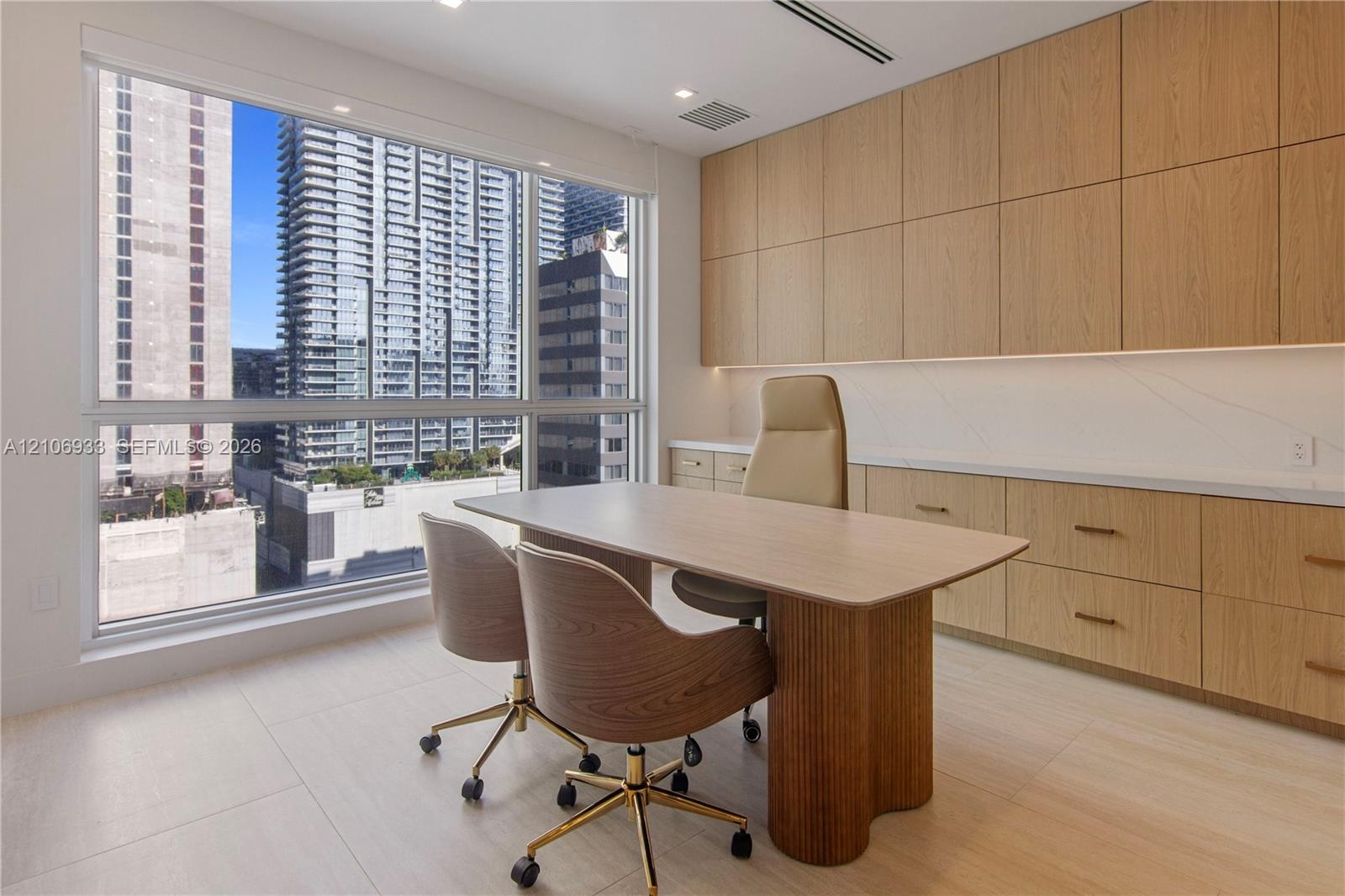 Large floor-to-ceiling window, custom floor-to-ceiling wood-finish cabinetry, solid-surface countertops, and light-toned large-format tile flooring