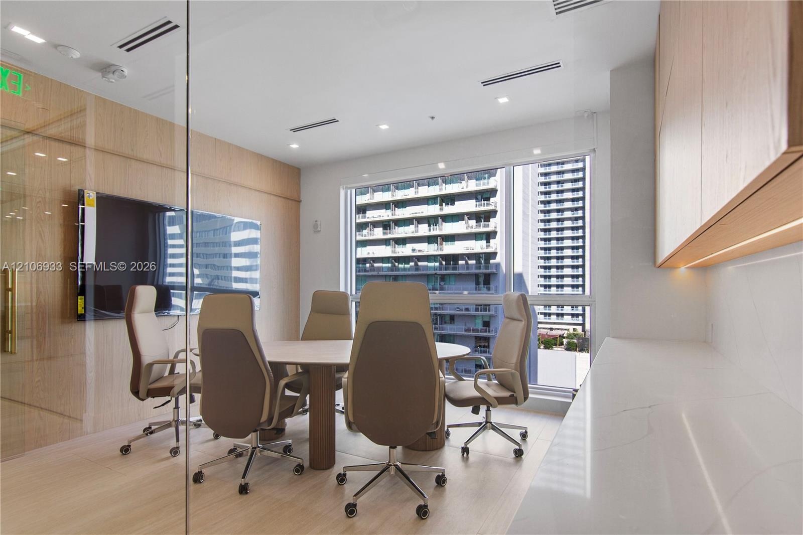 Glass-enclosed room featuring wood-finish paneling, floor-to-ceiling windows, integrated under-cabinet lighting, and a stone-surface built-in counter