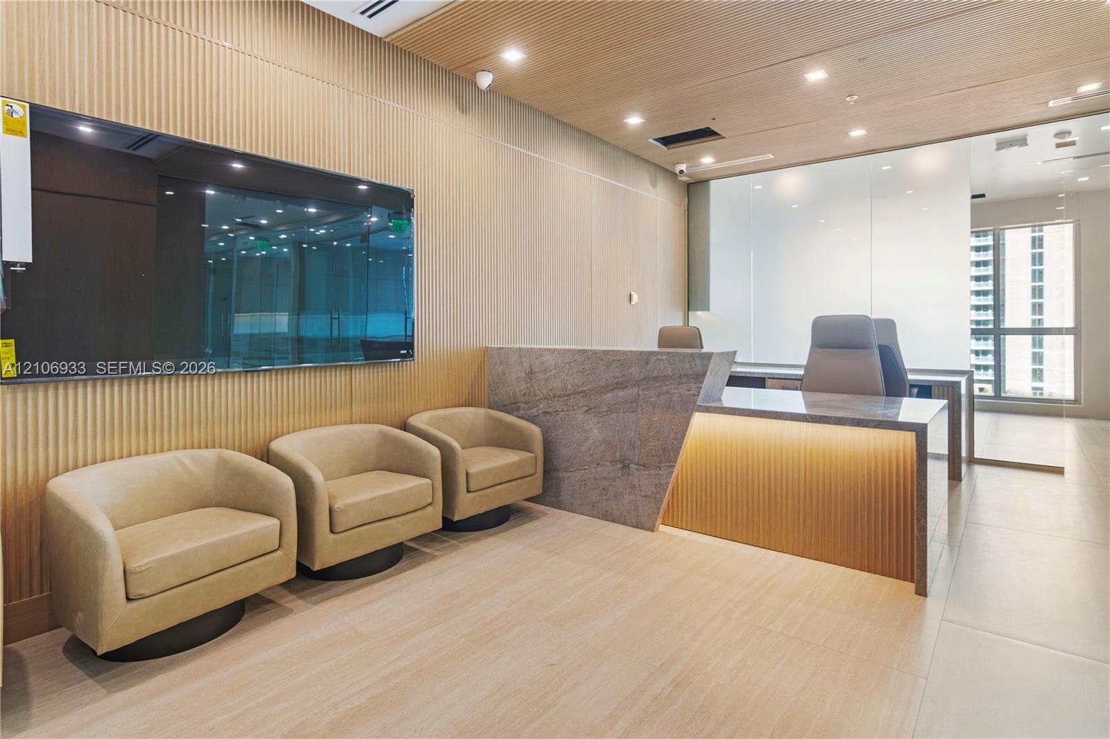 Reception area featuring vertical wood-slat wall paneling, stone-front desk with integrated lighting, wood-finish ceiling, and recessed lighting