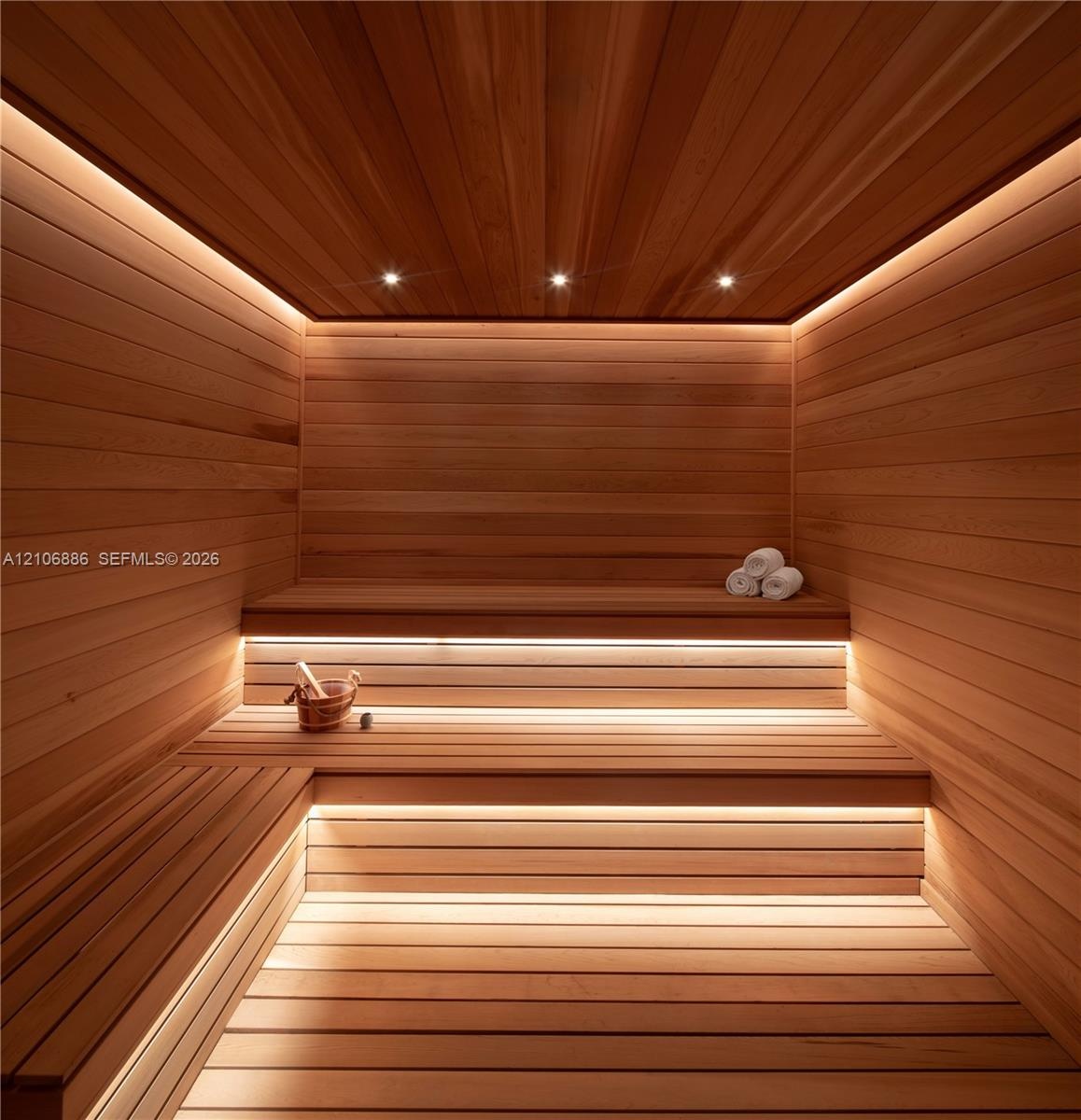 Custom-built sauna featuring tongue-and-groove wood paneling, multi-level tiered benches, recessed ceiling lighting, and integrated linear LED accent 