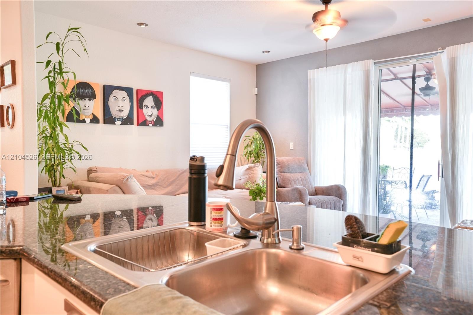 Kitchen island featuring a stone countertop, dual-basin stainless steel undermount sink, and a high-arch pull-down faucet
