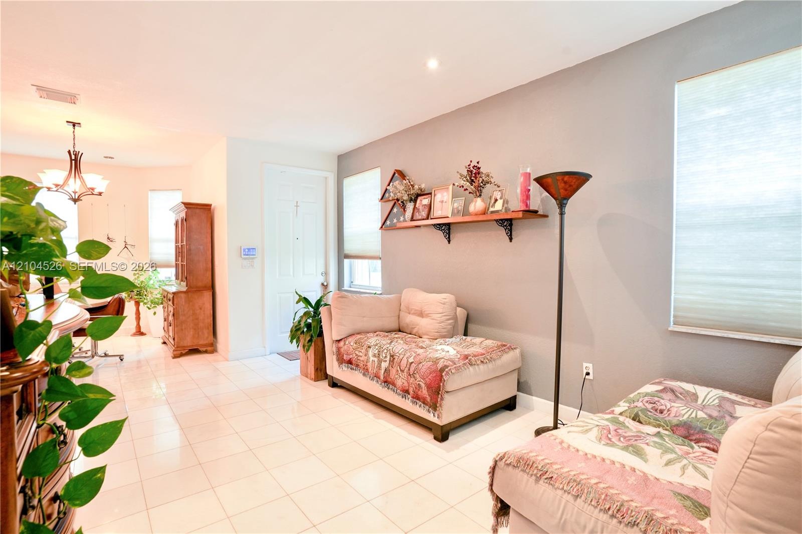 Light-toned tile flooring, recessed ceiling lighting, multi-paneled entry door, and large windows with cellular shades