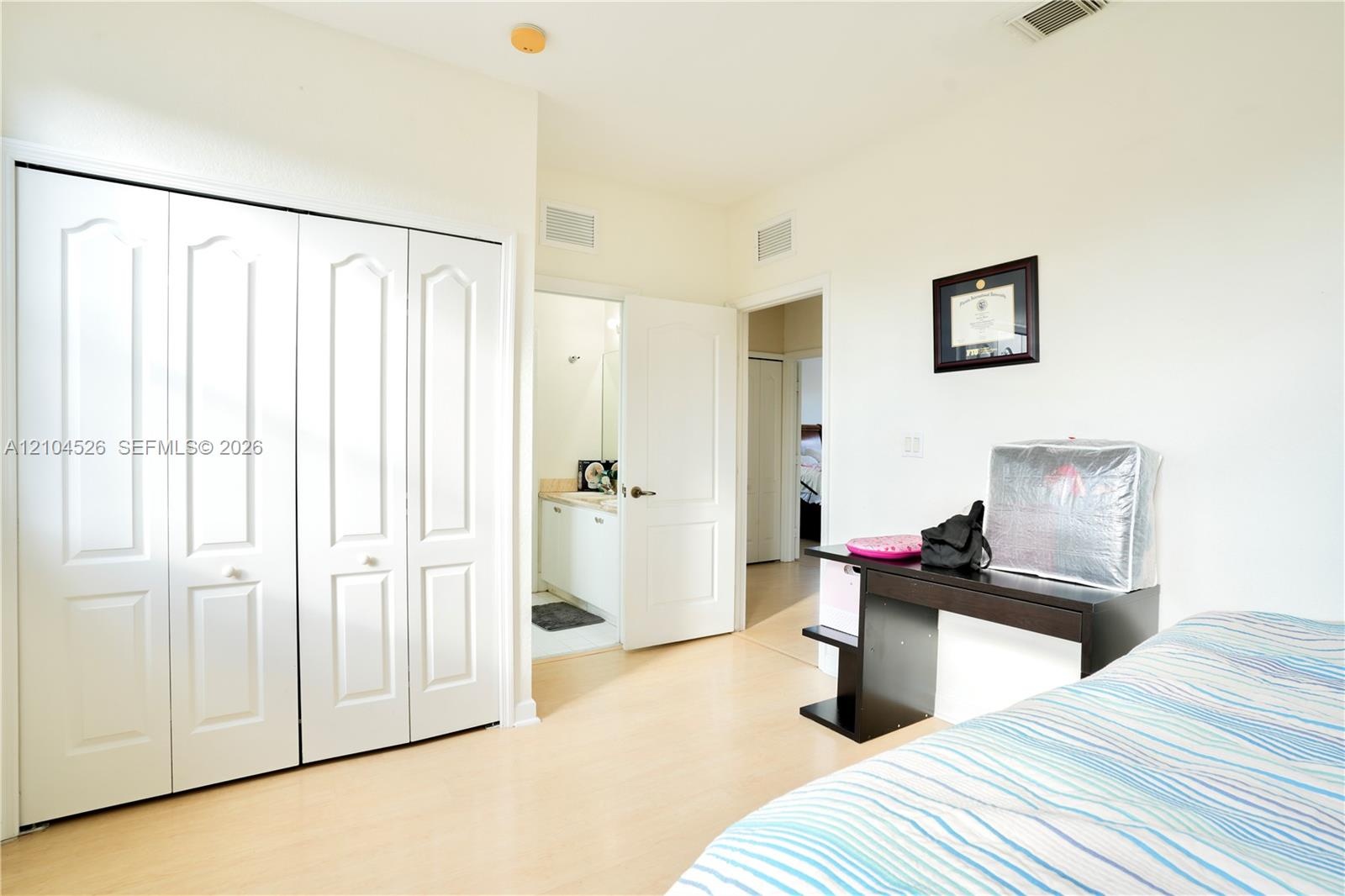 Interior space featuring wood-finish flooring, white walls, and a multi-panel bifold closet door