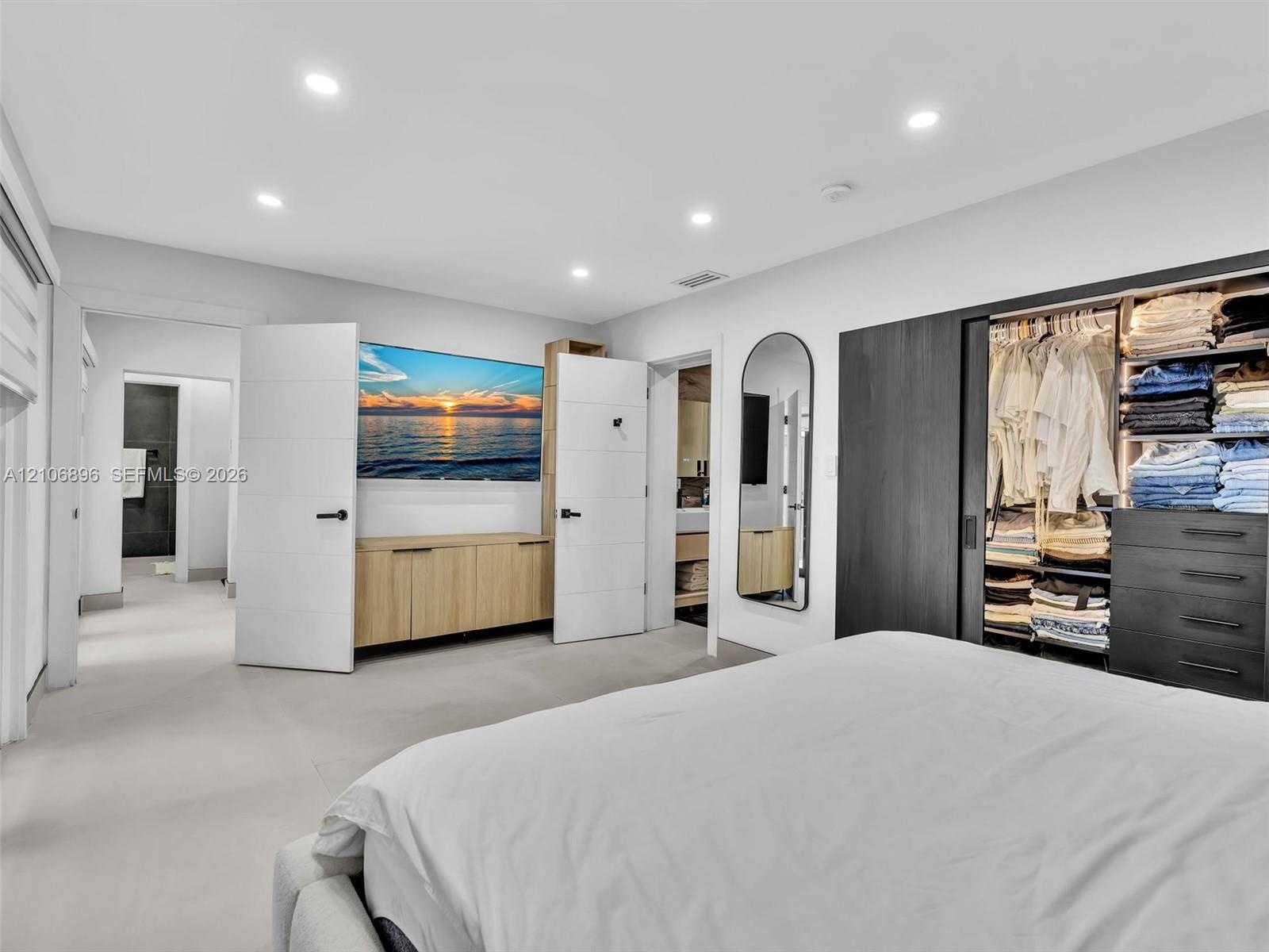 Recessed lighting, built-in light-wood cabinetry, dark wood-finish sliding closet doors with integrated shelving and drawer storage, and wall-mounted 