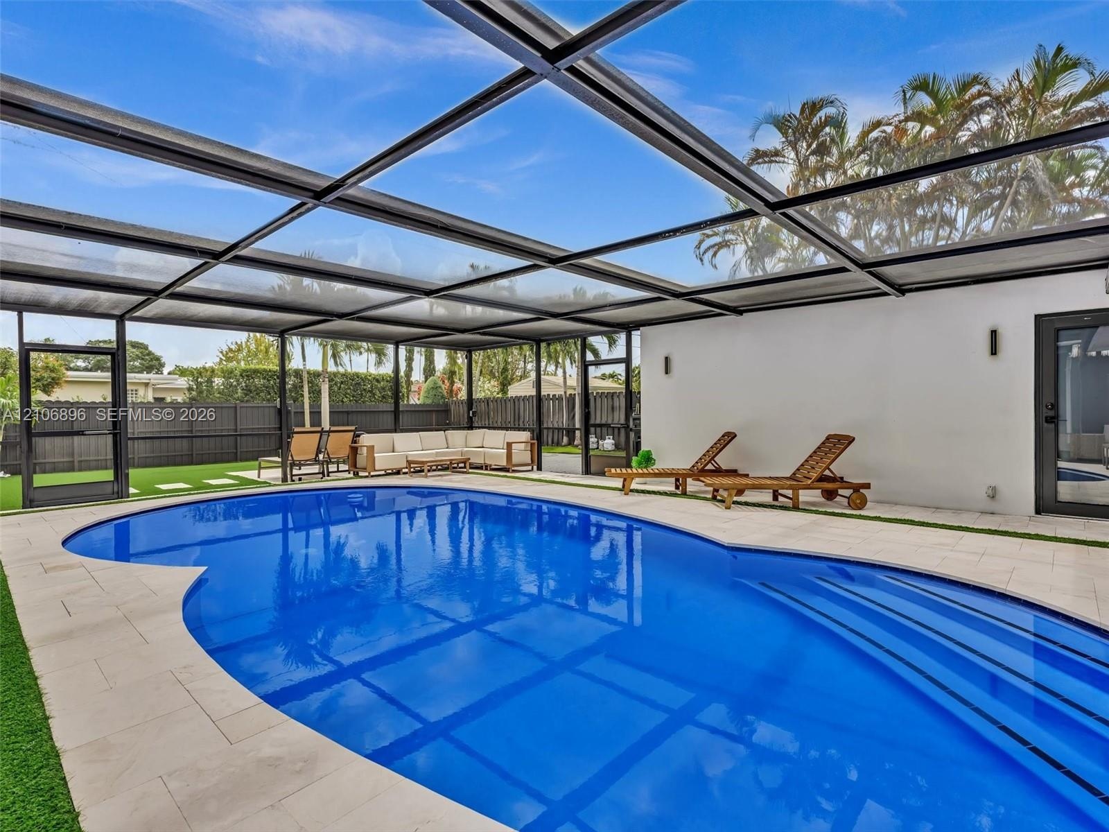 Screened-in patio featuring a swimming pool with integrated steps, tile decking, and artificial turf perimeter