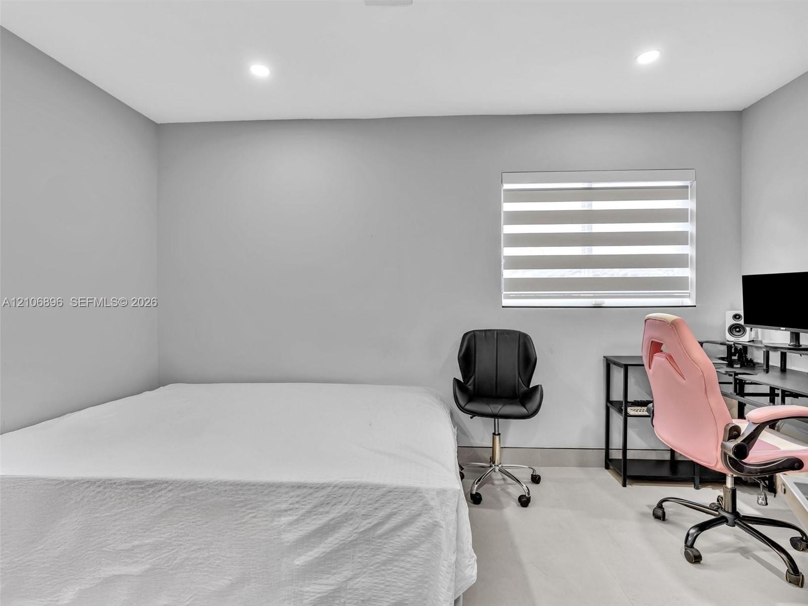 Room featuring neutral-toned walls, recessed lighting, and a window equipped with banded roller shades