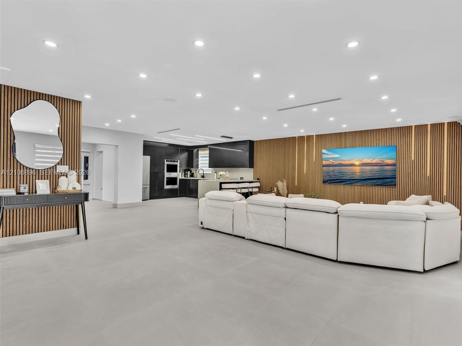 Large open interior space featuring vertical wood-slat accent walls, recessed ceiling lighting, and neutral large-format tile flooring