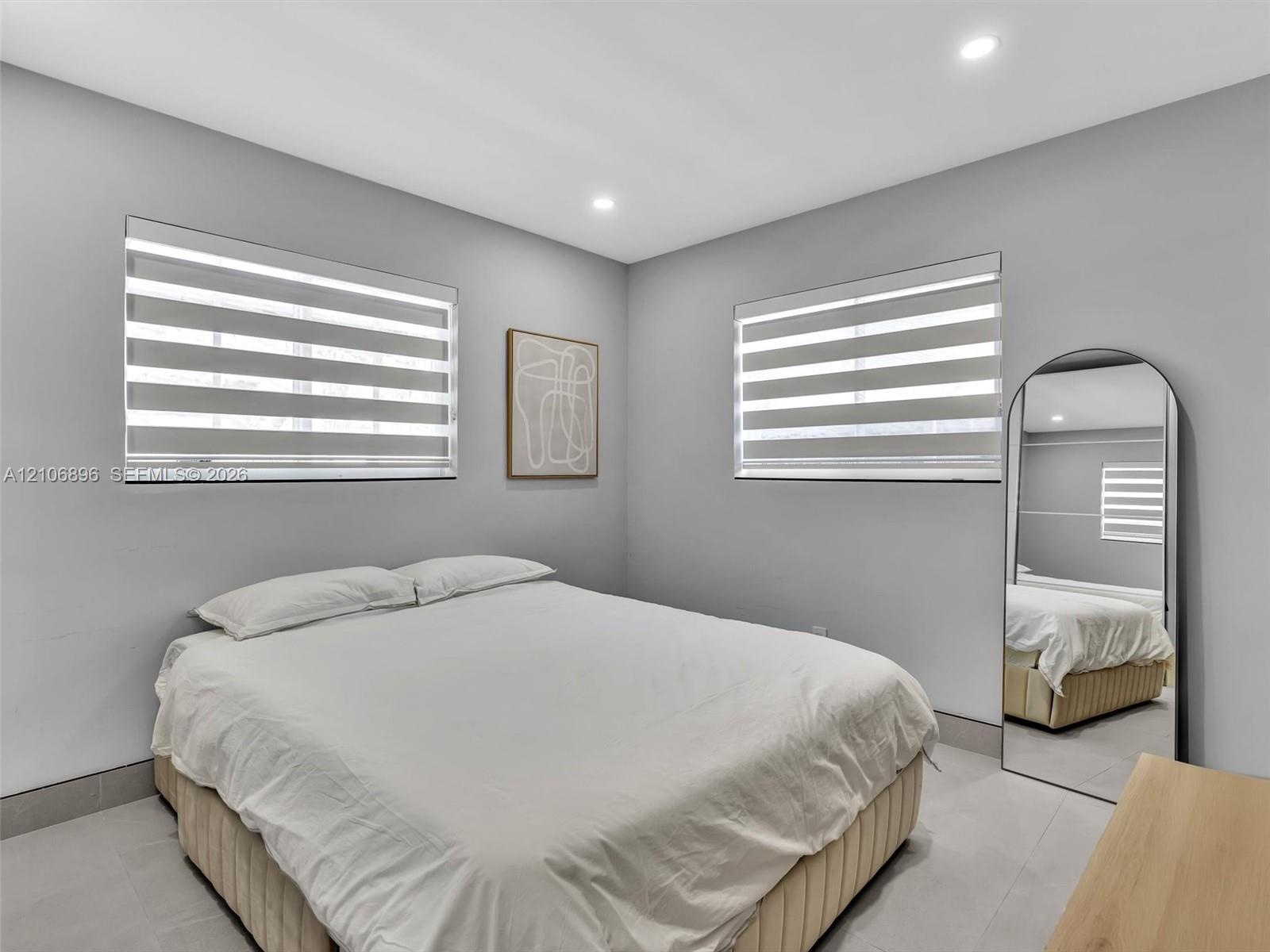 Neutral wall tones featuring dual-tone striped window shades and recessed ceiling lighting throughout