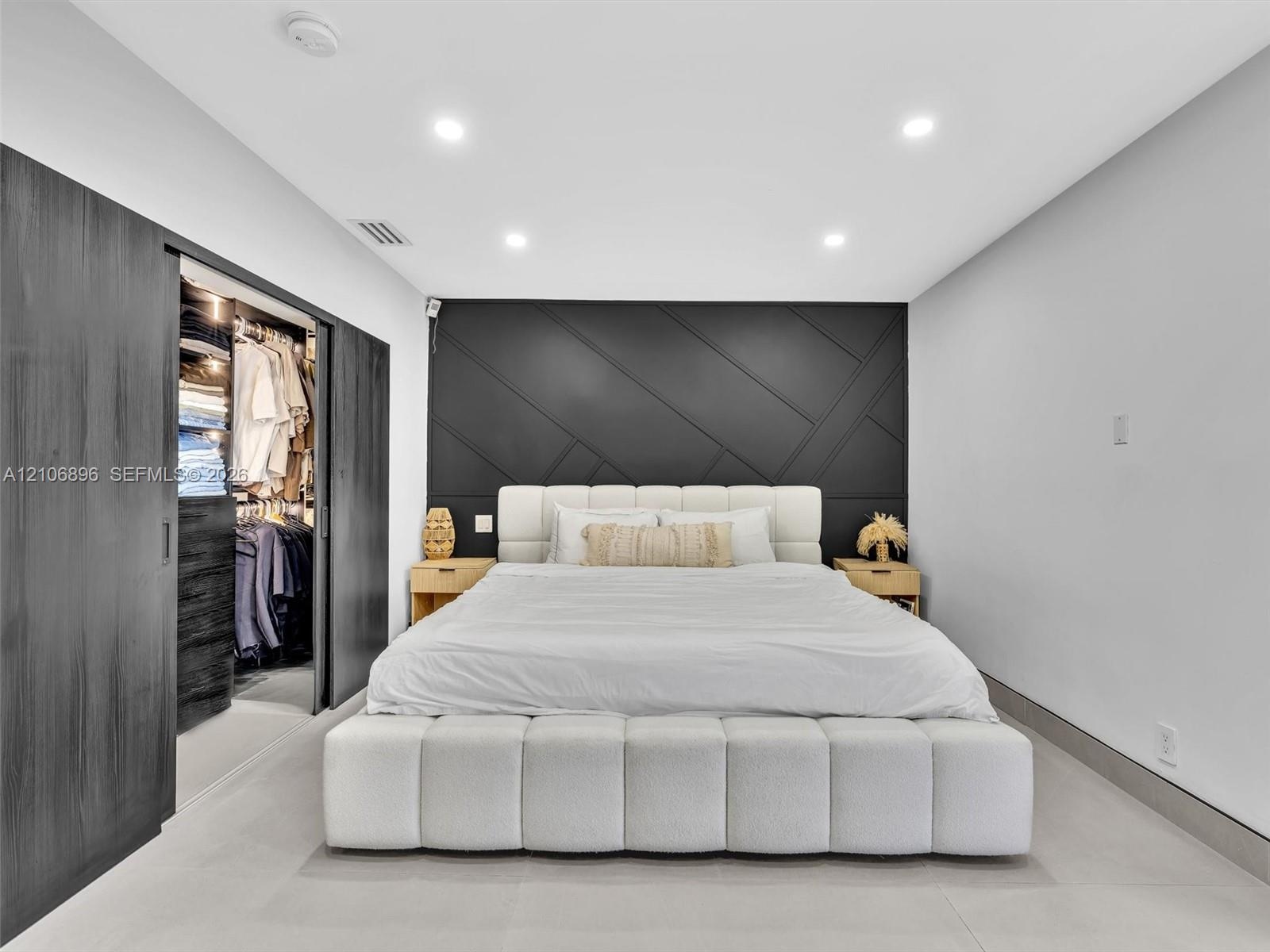 Interior room featuring a geometric paneled charcoal accent wall, recessed lighting, and large-format tile flooring
