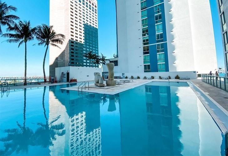 Outdoor swimming pool featuring a central island with abstract sculpture, tile surround, and metal railings