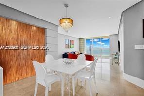 Textured wood-panel accent wall, pendant lighting fixture, and floor-to-ceiling glass paneling with water backdrop