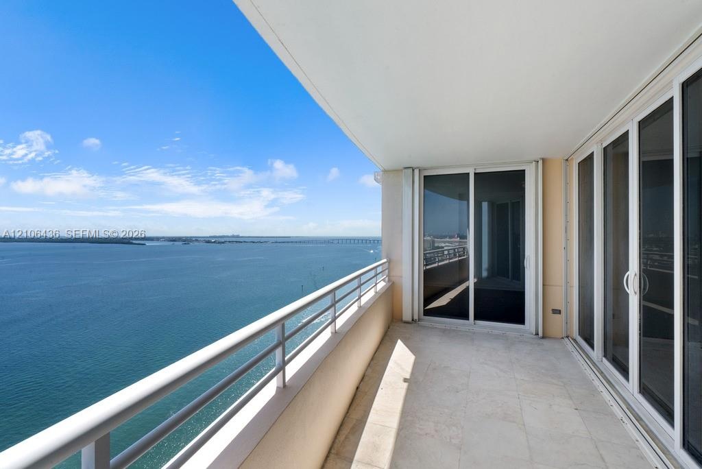 Covered balcony featuring stone tile flooring, a horizontal metal railing, and sliding glass door entry