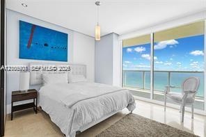 Floor-to-ceiling glass sliding doors, polished tile flooring, recessed ceiling lighting, and a pendant light fixture