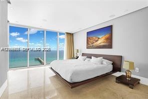 Floor-to-ceiling glass panel walls, light-toned stone flooring, and recessed ceiling lighting