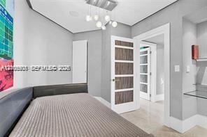 Contemporary interior featuring a multi-light globe chandelier, wood-grain panel doors, glass-paneled interior doors, built-in glass shelving, and neu