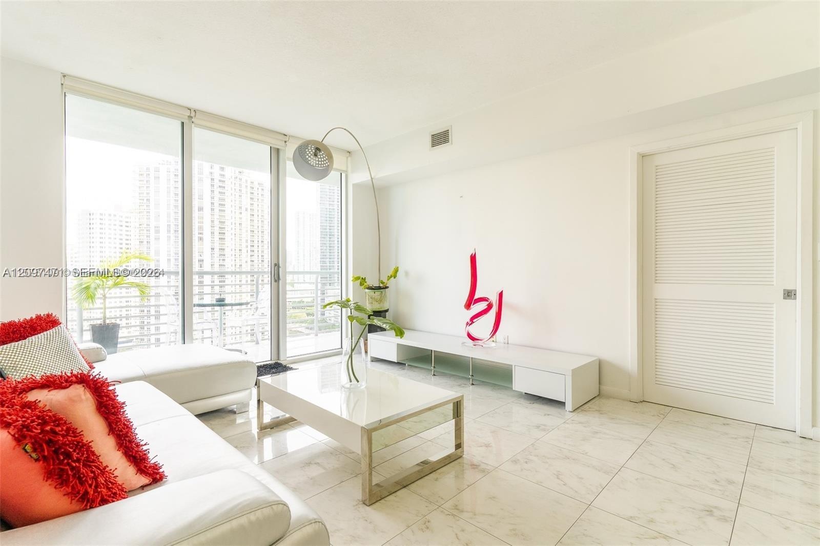 Living area featuring floor-to-ceiling glass sliding doors, stone-finish tile flooring, and a louvered interior door