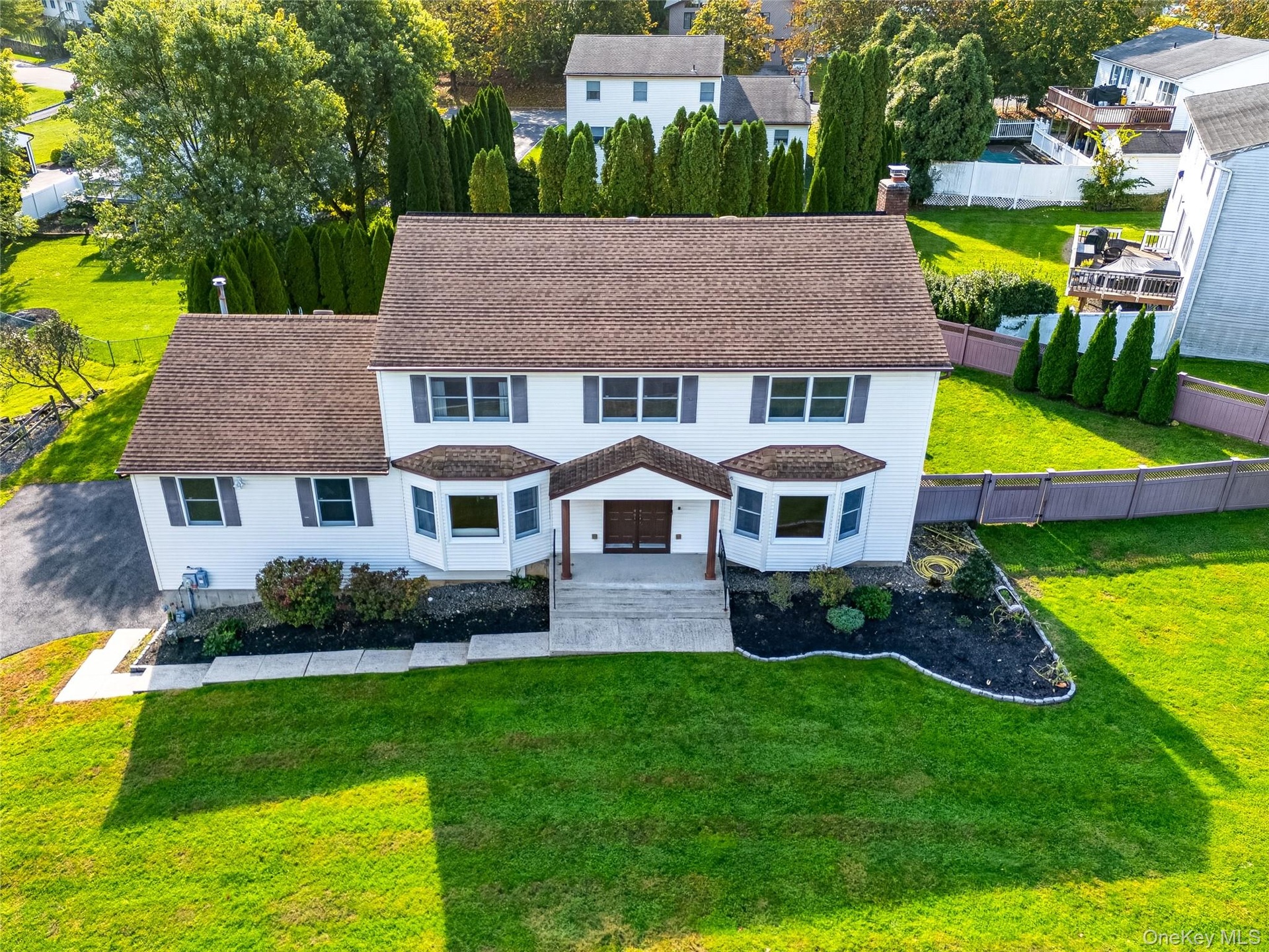 Two-story colonial residence featuring  siding, a multi-gabled roofline, dual front-facing bay windows, and a covered entryway with a  walkway