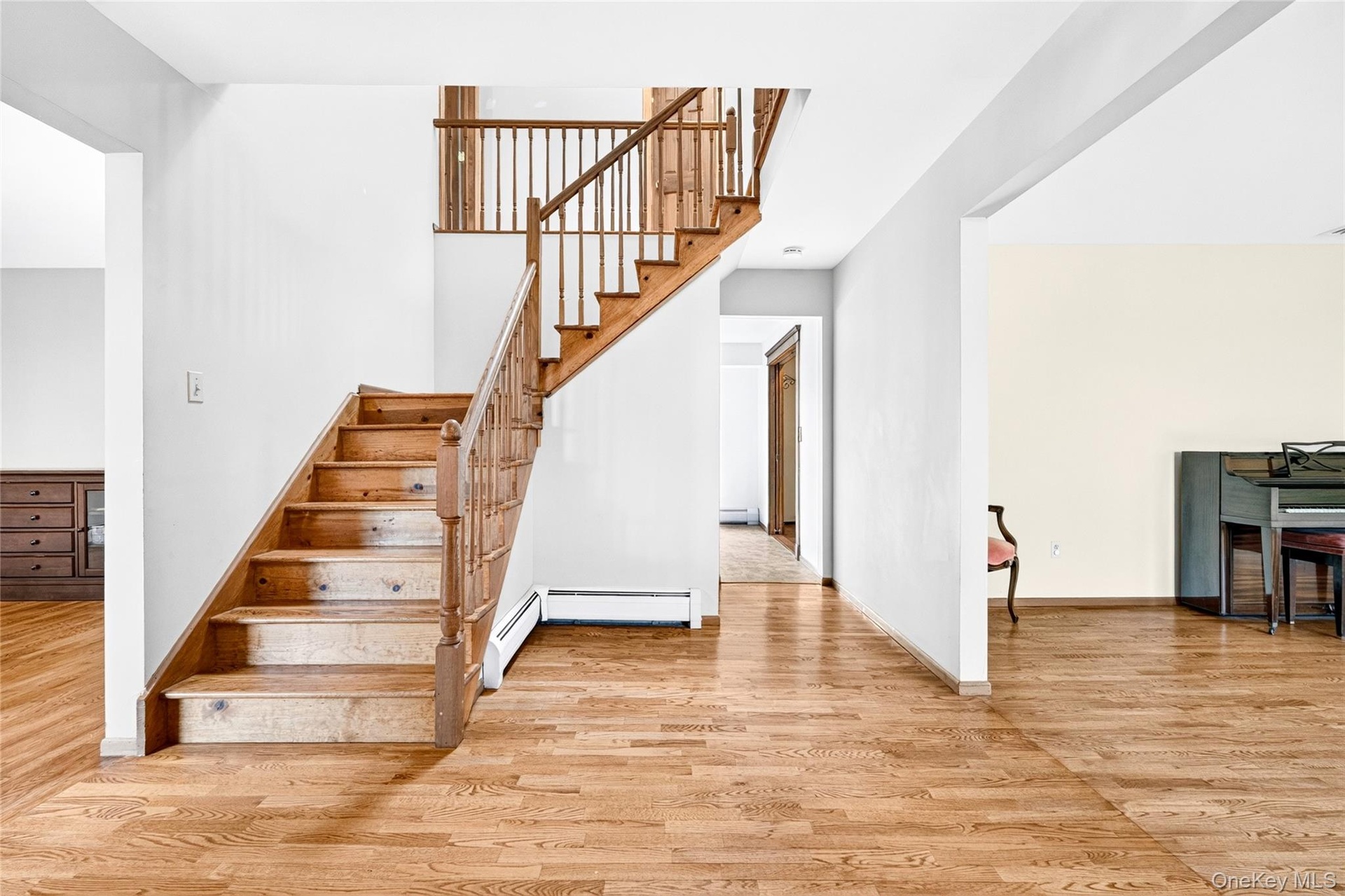 Foyer featuring wood-finish flooring and a central staircase with wood balusters and a polished wood handrail