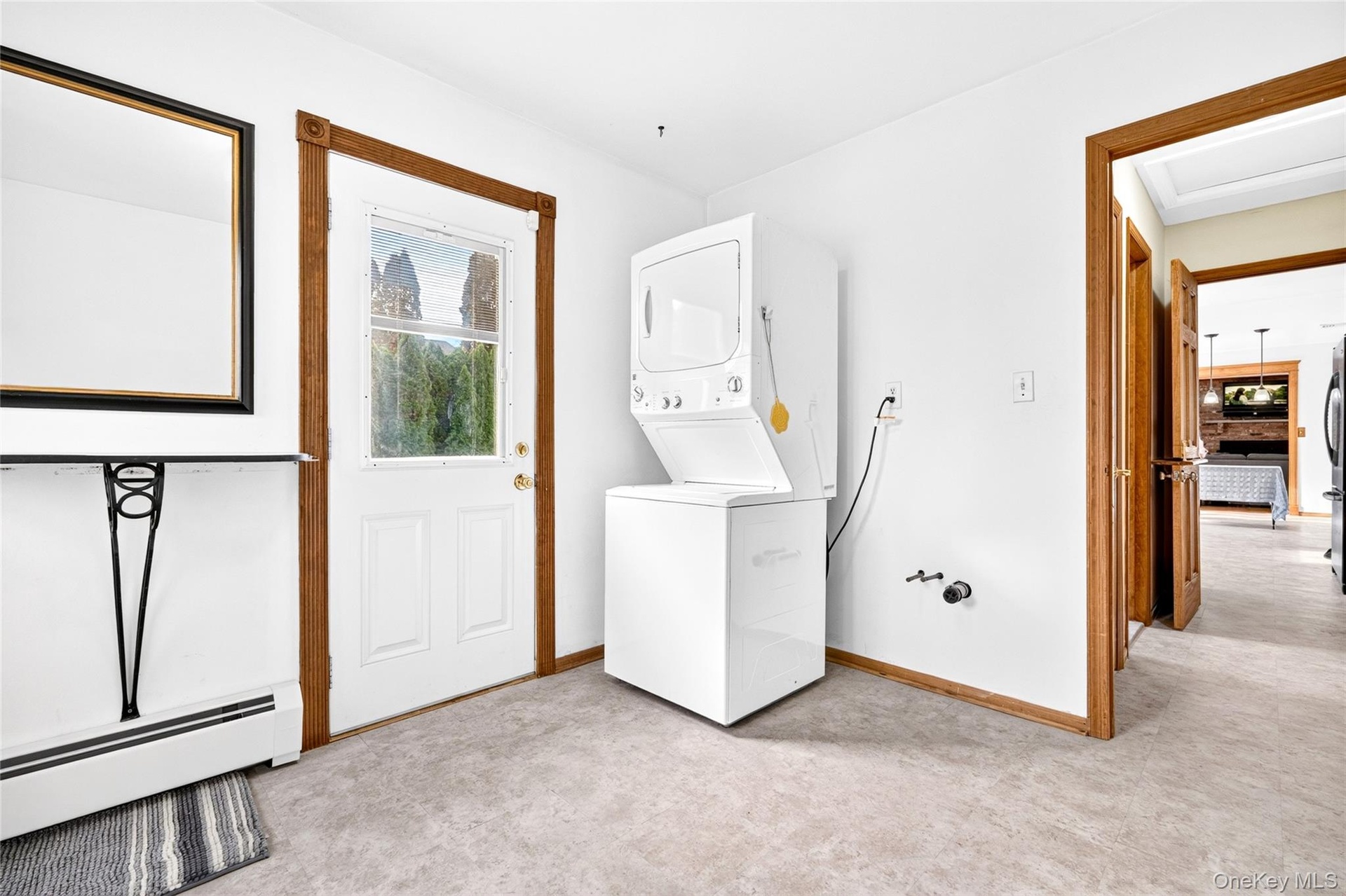 Utility space featuring a stacked washer and dryer unit, an exterior door with a glass insert, and wood-trim finishes