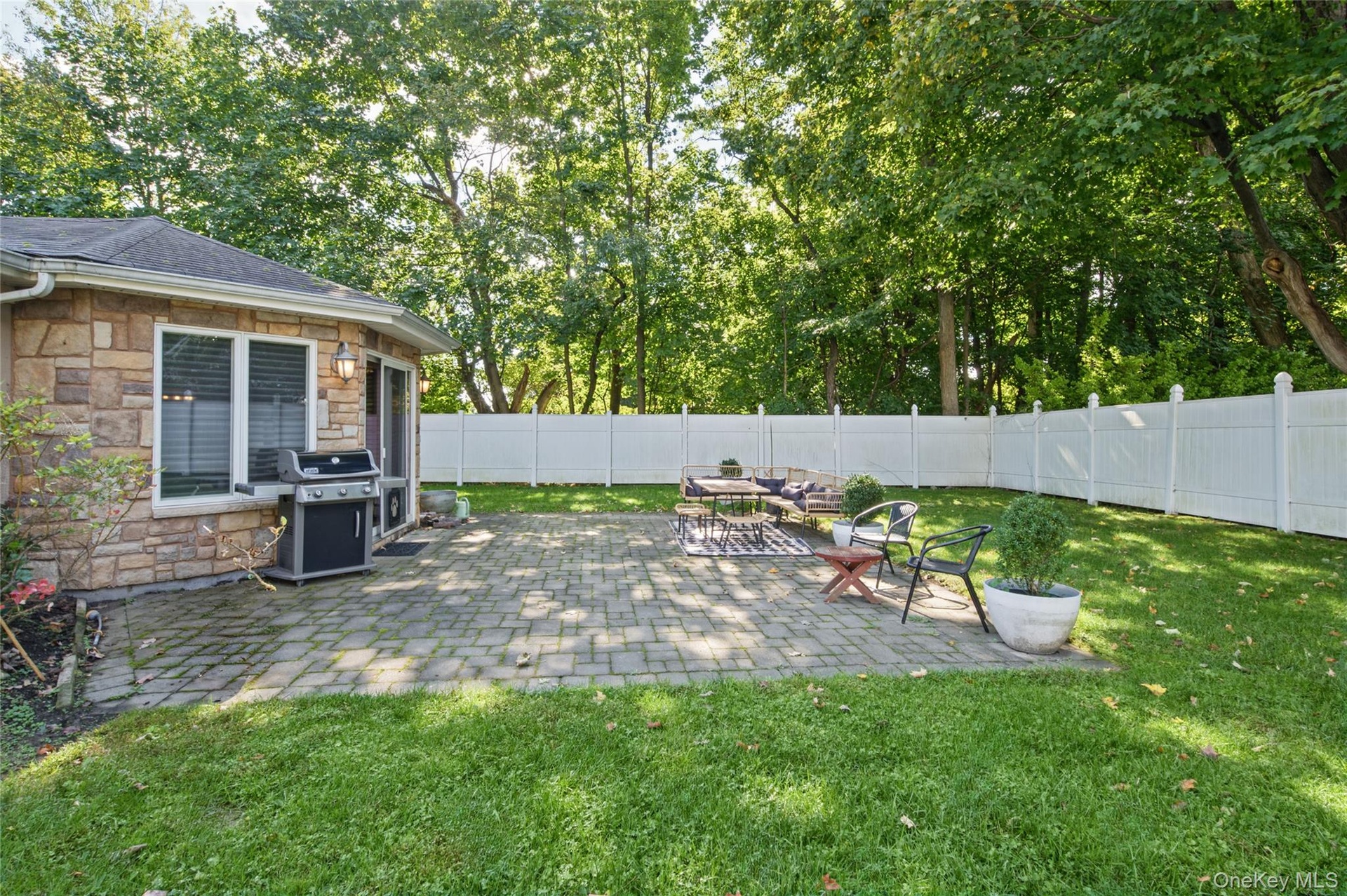 Stone-veneer exterior, paved patio, and white privacy fencing