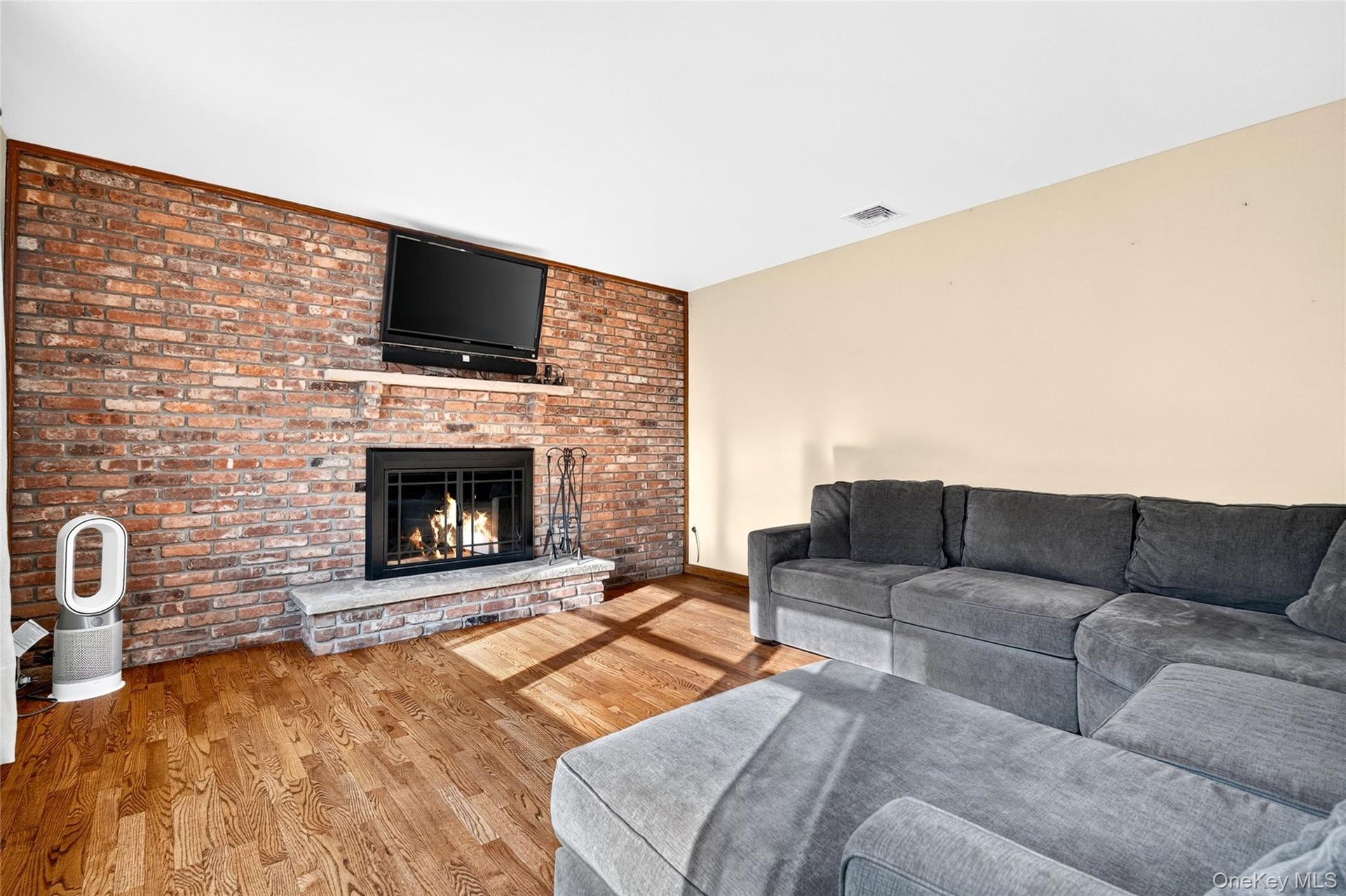 Full-height brick accent wall featuring an integrated wood-burning fireplace, raised stone hearth, and built-in wooden mantelpiece, complemented by ha