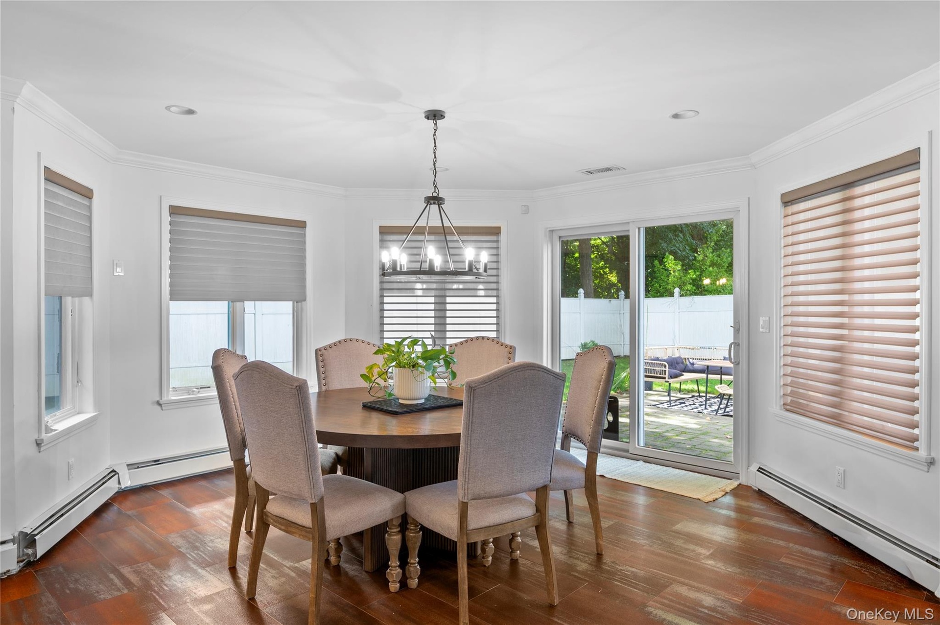 Bay-style dining area featuring wood-finish flooring, crown molding, recessed lighting, an architectural metal chandelier, and sliding glass doors