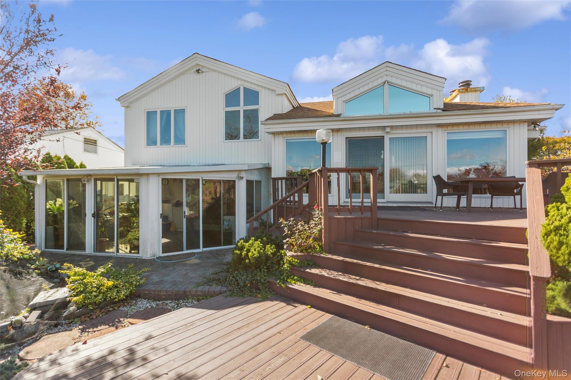 Rear view of property with a deck, a sunroom, and a chimney