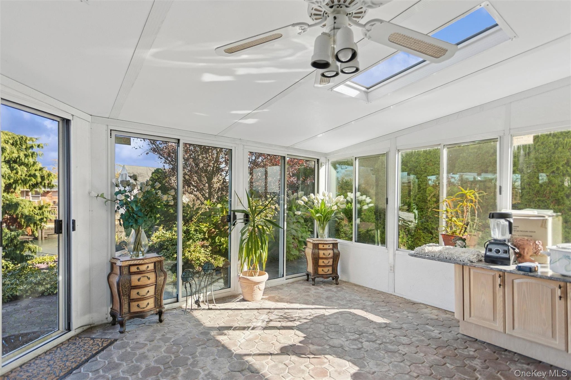 Sunroom featuring healthy amount of natural light, lofted ceiling, stone finish flooring, and a skylight